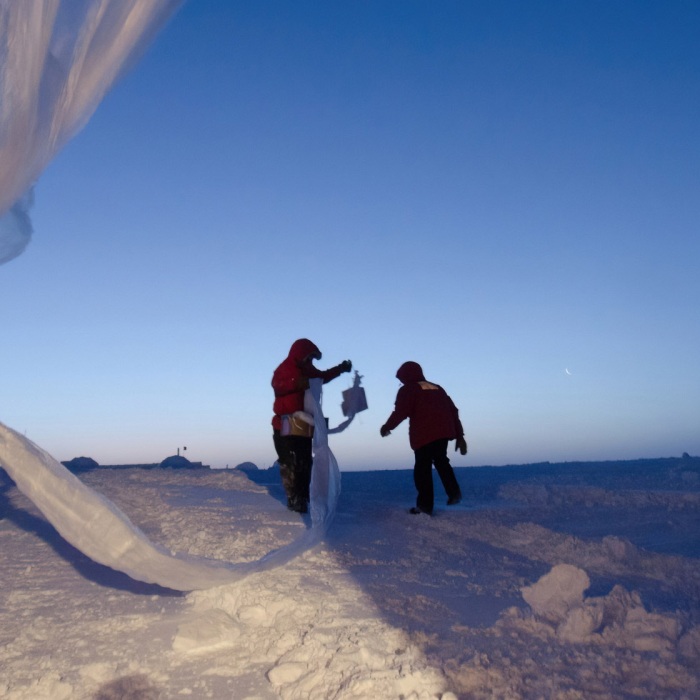 Researchers launching weather balloons in Antarctica at dusk