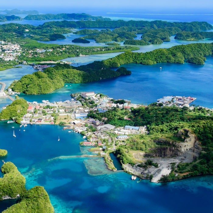 Aerial view of Palau Malakal Island and Koror, a world heritage site surrounded by sapphire blue waters and coral reefs and covered in bright green vegetation.