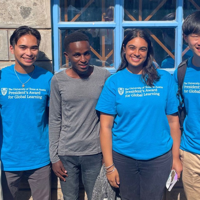 Group of smiling students wearing blue President's award shirts.
