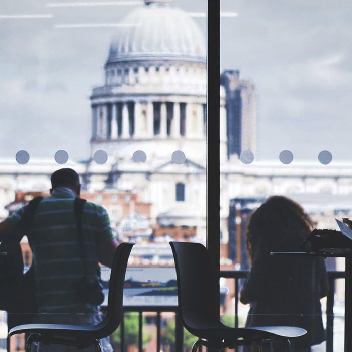 Students work against a panoramic windowed background showing the capitol building in Paris, France