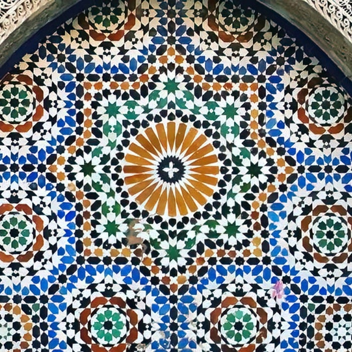 Moroccon tile is elegantly arranged on the side of a building with intricate architectural detail and flourishes