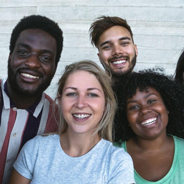 a diverse group of young adults smile for a group photo