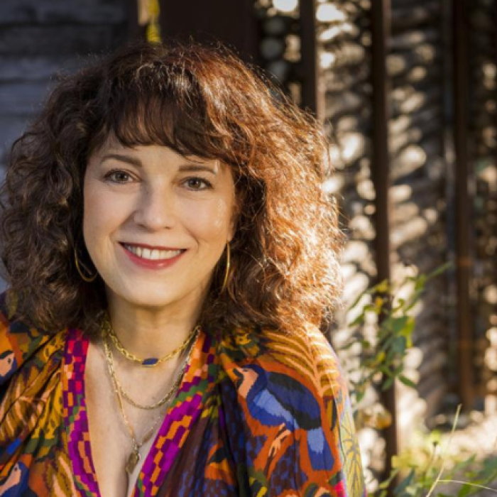 Estrella Acosta jazz vocalist smiles at the camera wearing a colorful shirt in an outdoor setting