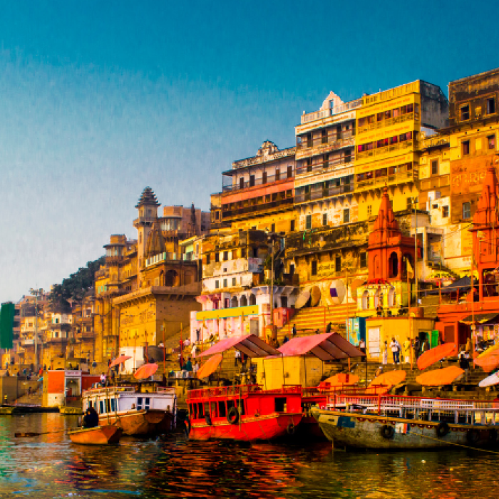 Colorful yellow, orange, and white buildings sit on the right side of a river with self-made boats in Asia