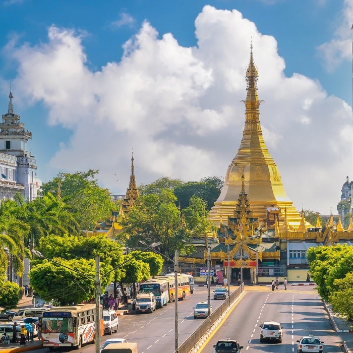 A view down the streets leading to Sule pagoda that stands proudly in downtown Yangon, Myanmar against a blue sky with puffy clouds