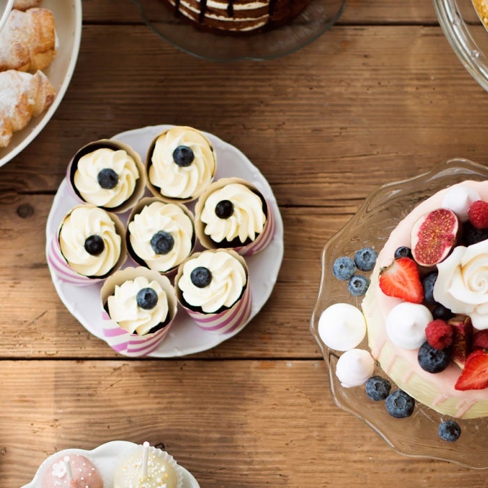 Wooden table with cake, pies, cupcakes, tarts and cake pops.