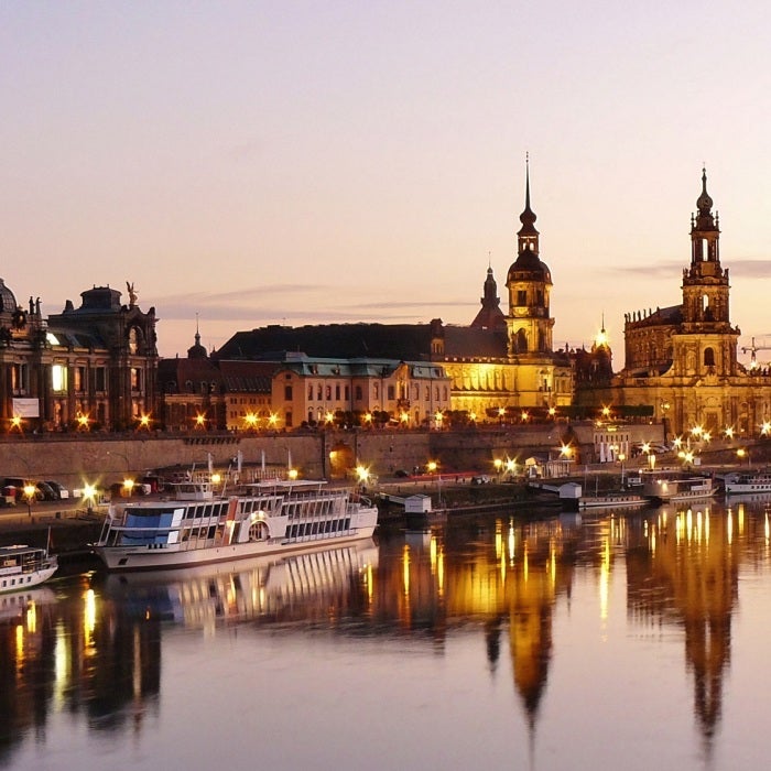 Illuminated buildings and boats during a sunset on the river in Dresden, Germany