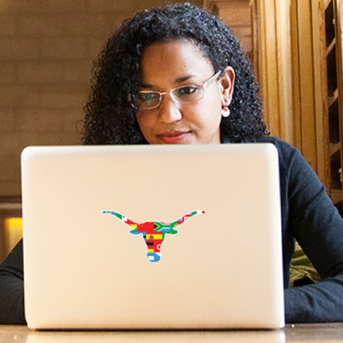 A person sitting behind their laptop with a Texas Global logo sticker on it