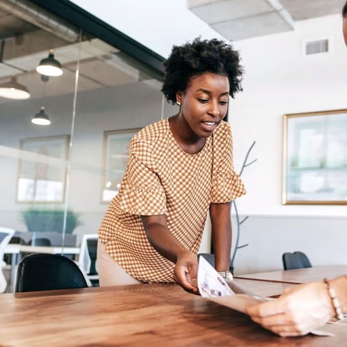 Two people have a talking in an office and going over a piece of paper