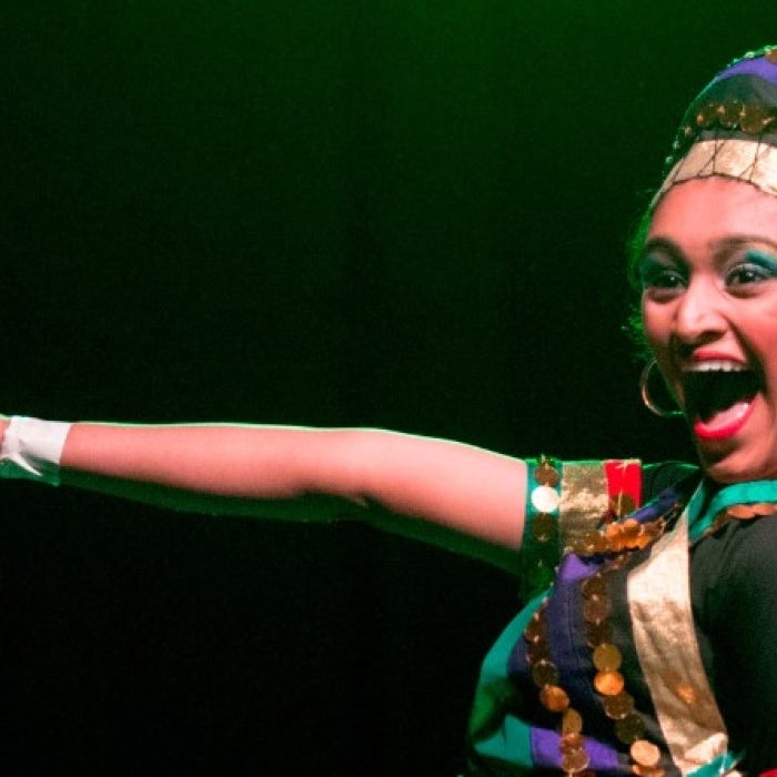 A dancer in traditional dress smiles. 