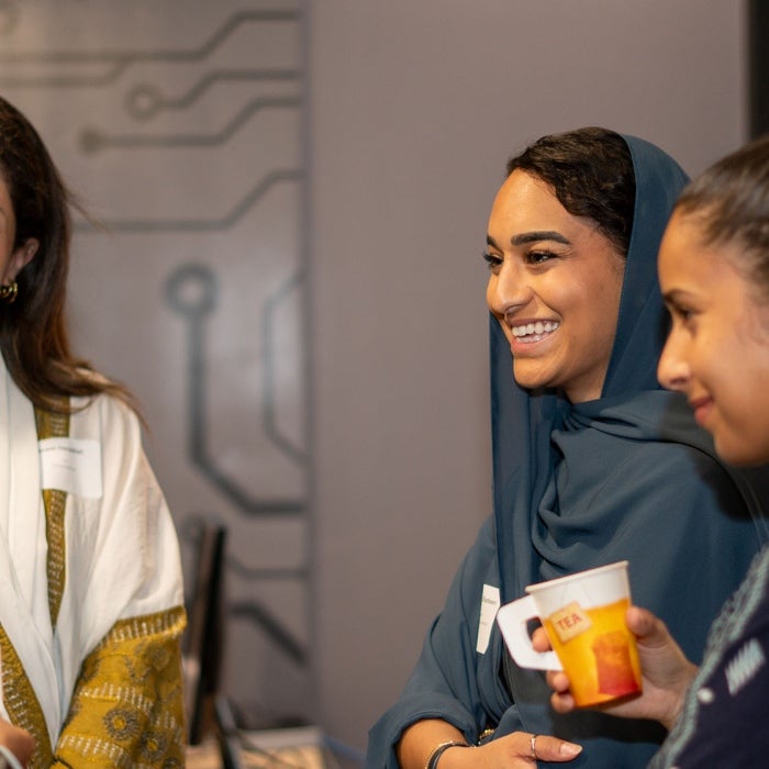 Female entrepreneurs smile as they gather and share about their experiences