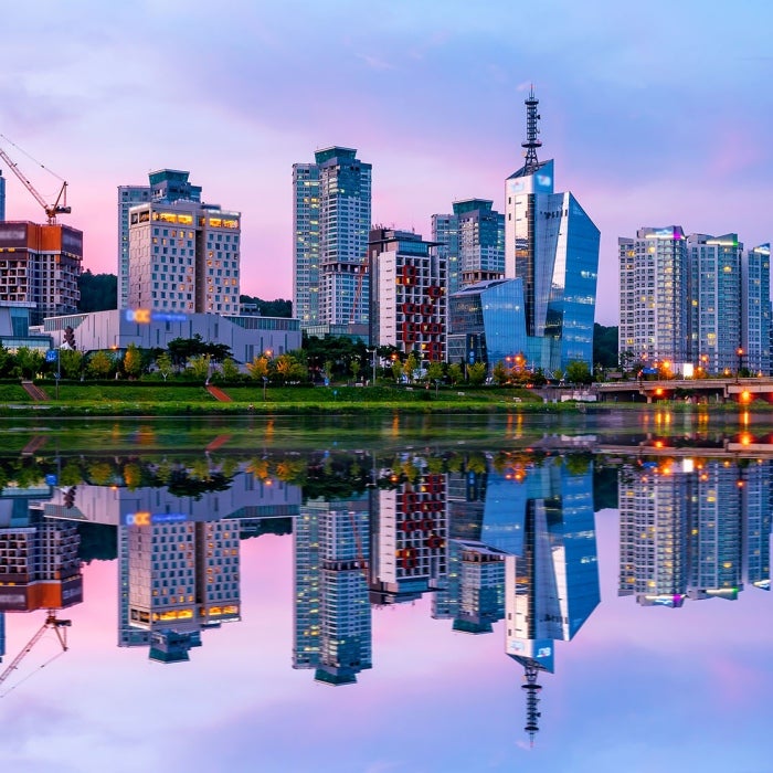 The city of Daejeon in South Korea is perfectly reflected in the river beside it against pink and blue sunset