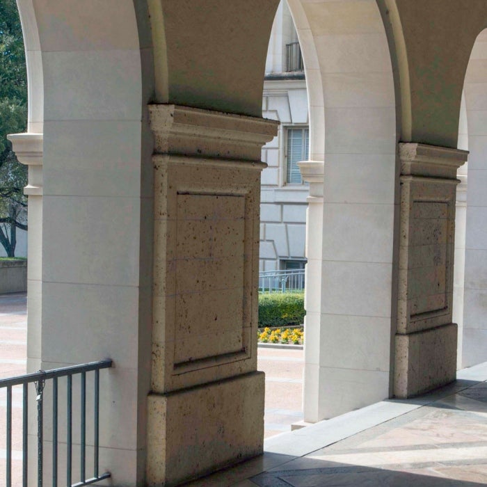 A student walks through the arches of the UT Main building that faces the Austin capitol