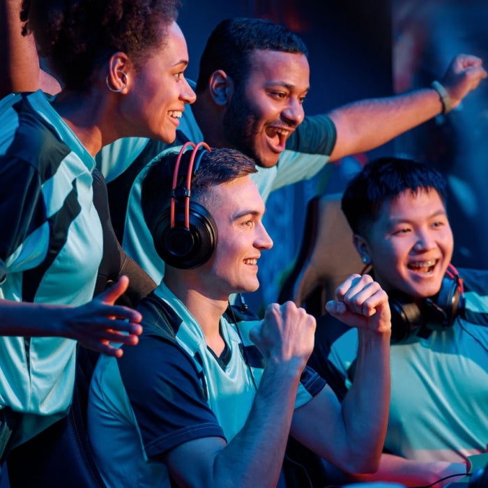 Multiracial students raising hands up and smiling during participation in esports/gaming