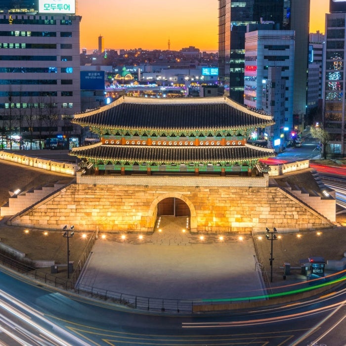 Colorfol blurred traffic lines from a slow exposure and tall office buildings with Namdaemun gate in the middle in Seoul, South Korea.
