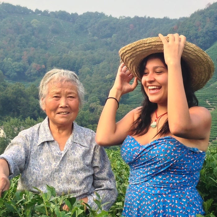 a young women adjusts her hat with a smile as she spends time with her family on a tea farm
