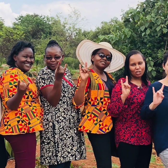 A smiling nursing group abroad poses while displaying the UT Hook'em signg