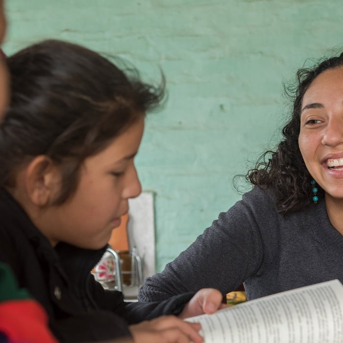 A female peace corps participant works with children in a school