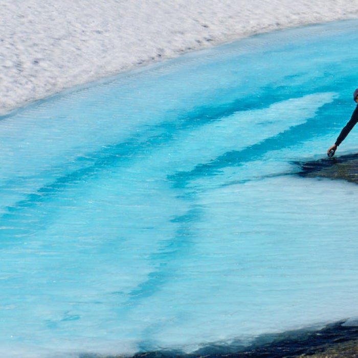 a young man fills a water bottle with fresh glacial water runoff