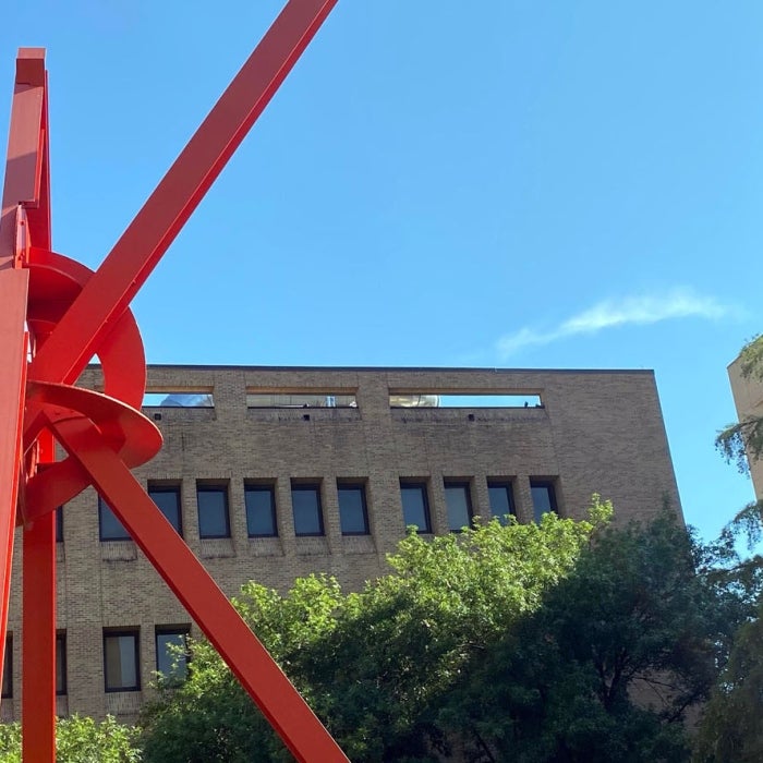 large red metal sculpture in front of the Cockrell School of Engineering buildings on the UT campus during the daytime