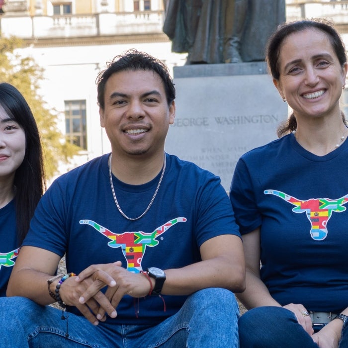 Diverse english language students smile and pose on campus wearing blue texas global shirts