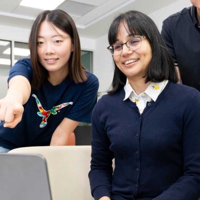 ISSS students smile while looking at a laptop screen