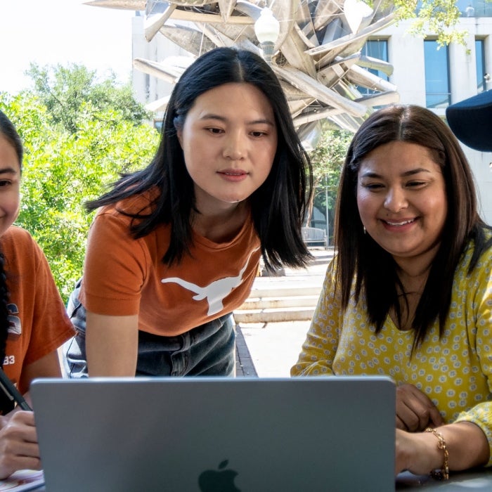 Students meet around a laptop on campus to apply for courses