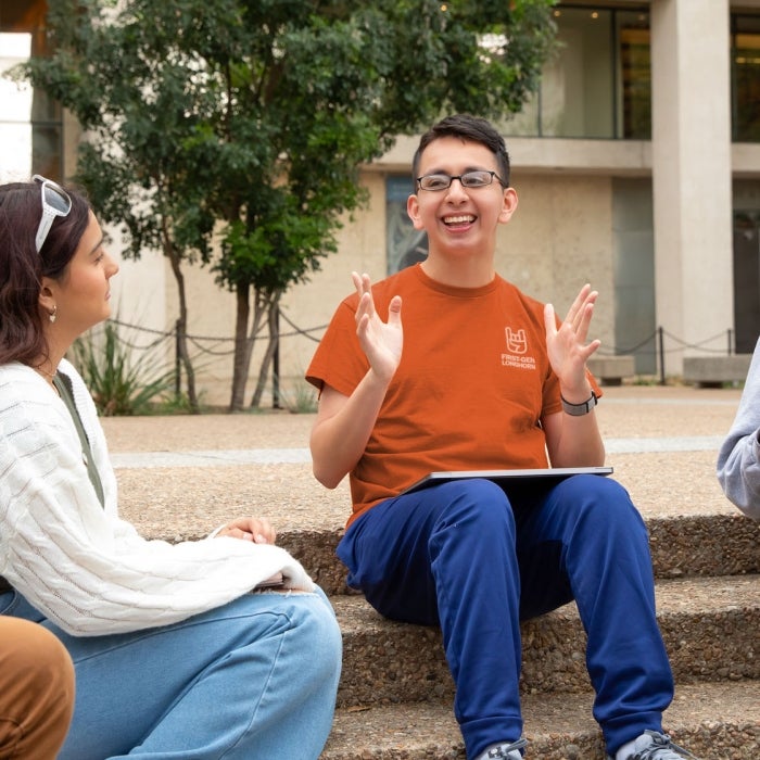 Students gather while sitting on some campus stairs outside as they enjoy talking together