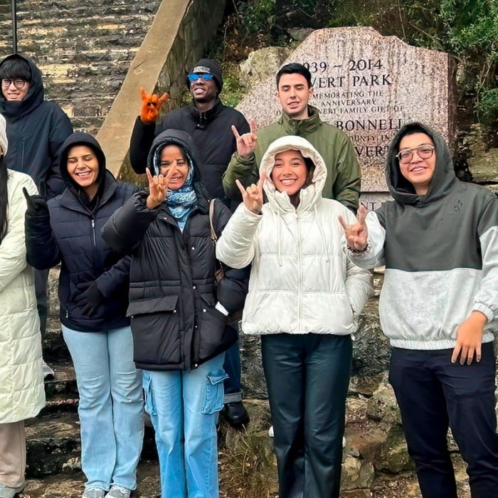 A group shows the hook'em sign while standing outside with winter coats on