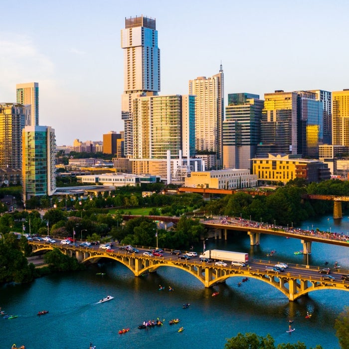 An aerial view of people enjoying Lady Bird Lake during the evening with the Austin skyline in view