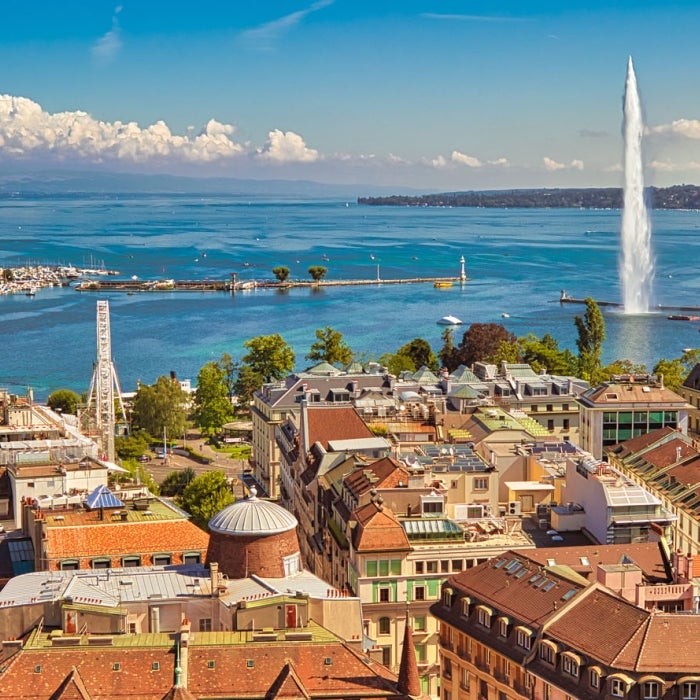 Aerial view of cityscape with Jet d'eau fountain in Lake Leman bay and harbor from the bell tower of Saint-Pierre Cathedral during a Sunny blue sky in Geneva, Switzerland