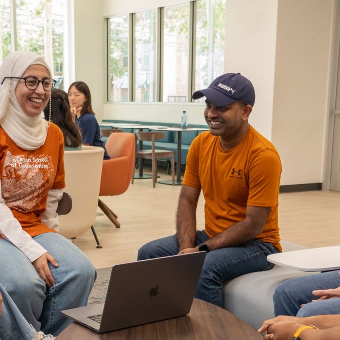 Smiling UT students sit together and talk in the Texas Global lounge