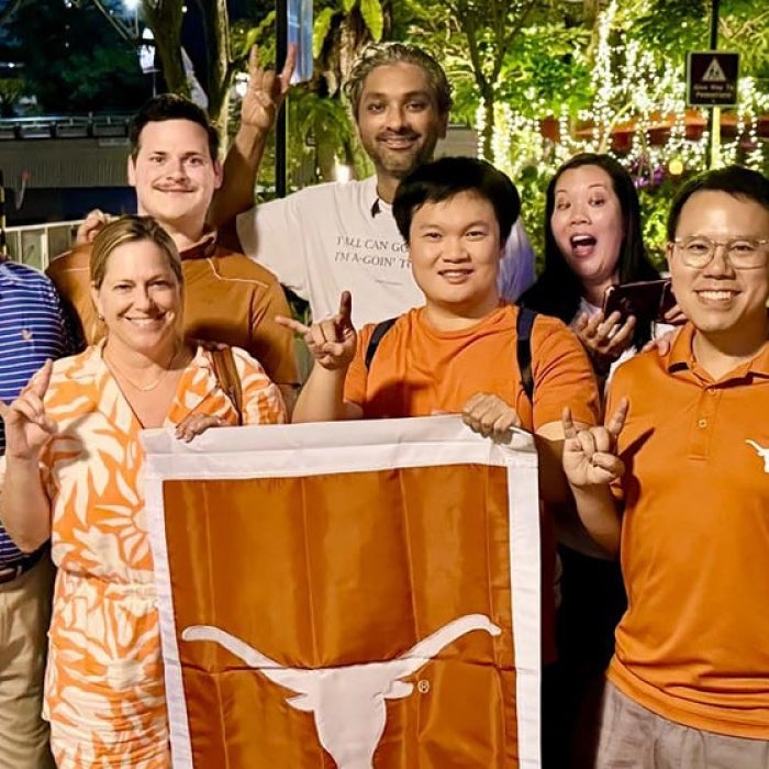 UT Alumni smile with the longhorn flag in Singapore