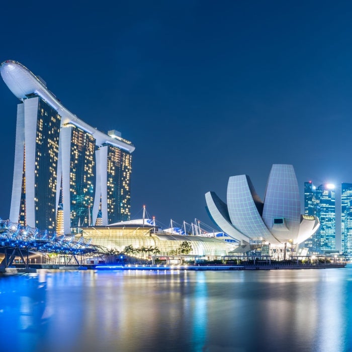 The skyline neon lights reflect off the still waters of the Marina Bay, Singapore