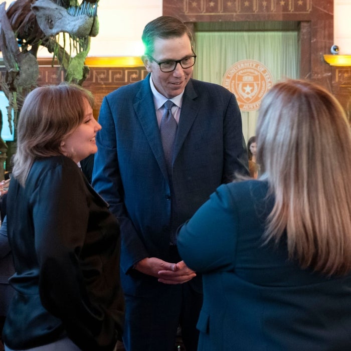 A scholar talks with two women at gathering at an event at the Texas Science & Natural History Museum