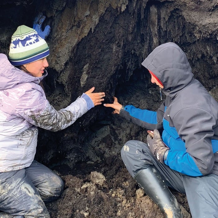 Two female researches look at the soil of an embankment