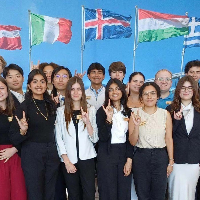 NATO student group poses in front of flags backdrop from various countries