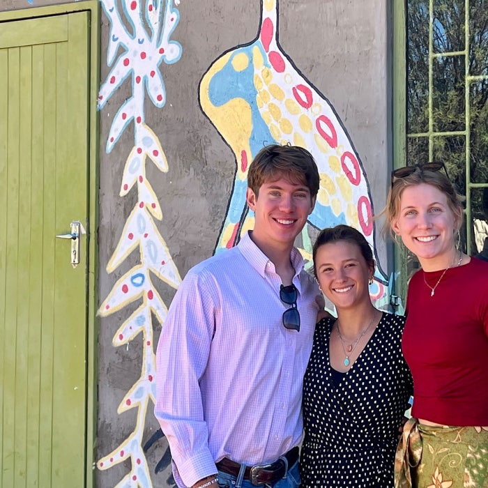 Students abroad pose in front of a concrete building with colorful depictions of animals