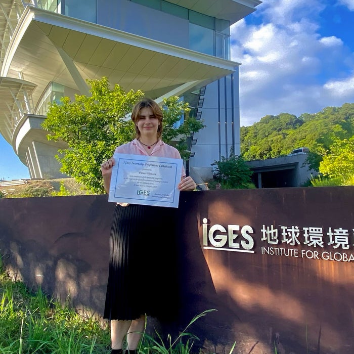 A female students stands in front of the IGES - Institute for Global Environmental Strategies in Japan on a sunny day