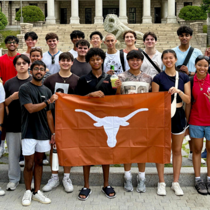 Take the World by the Horns program participants standing in front of building with Longhorn flag