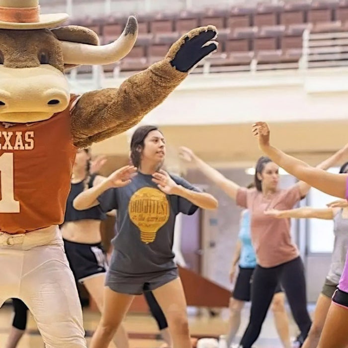 Students participate in a pilates class with the Bevo mascot in the Gregory Gym at UT Austin