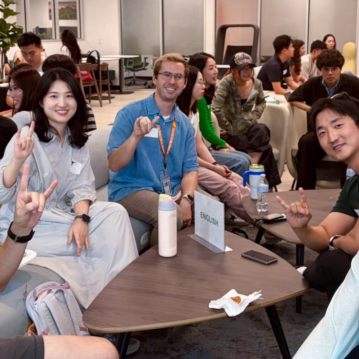 Smiling students participating in language circles of Korean, English, and Spanish