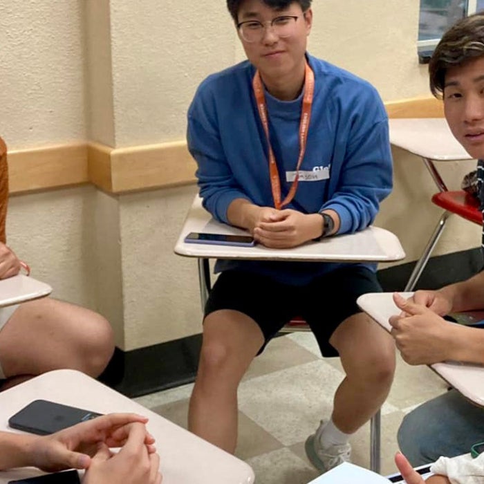  a mix of students smiling at the camera in a circle discussing language amongst each other