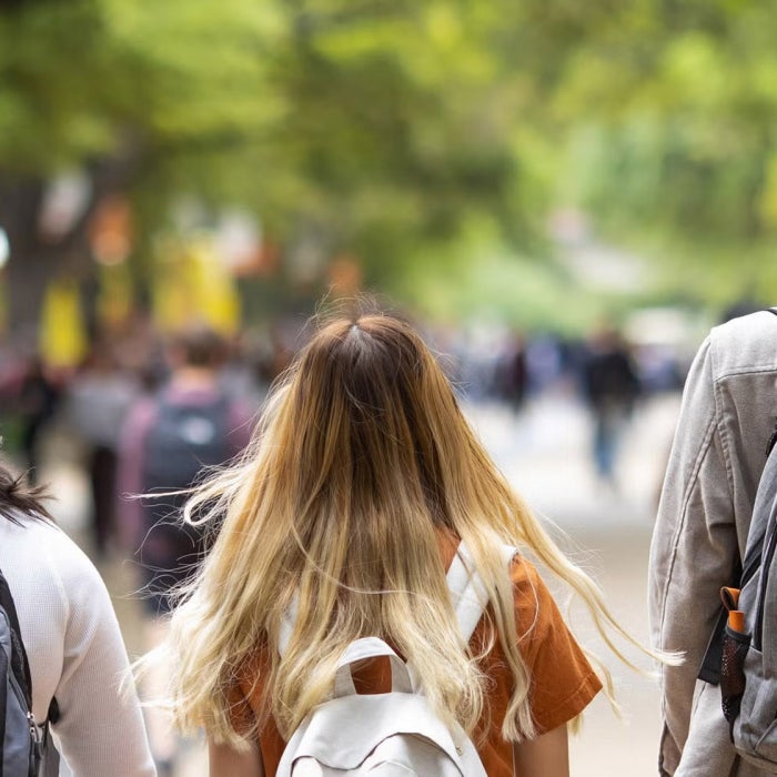A mix of students walking down speedway wearing backbacks