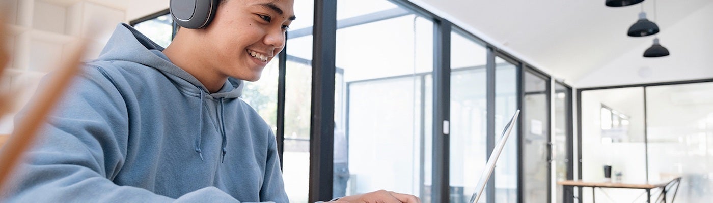 A student smiles while working on his laptop.