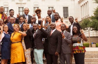 Recipients of the Mandela Washington Fellowship pose in front of the UT tower with hook 'em horns hand sign 