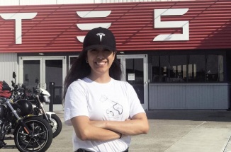 UT student Alejandra Hernandez poses for the camera in front of a TESLA store 
