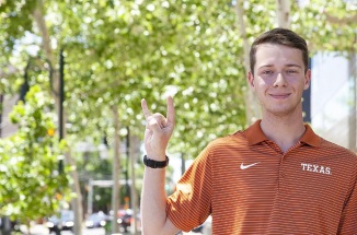 UT student Cameron Goff wears UT austin polo shirt and holds a hook 'em horns hand sign 