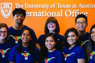 Education Abroad Peers pose for a picture in front of the International Office Logo 