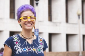UT Student Yenibel Ruiz poses with a smile and short, bright purple hair. 